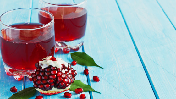 ripe pomegranate seeds and fresh pomegranate juice on a blue wooden background.health and diet food. copy space background